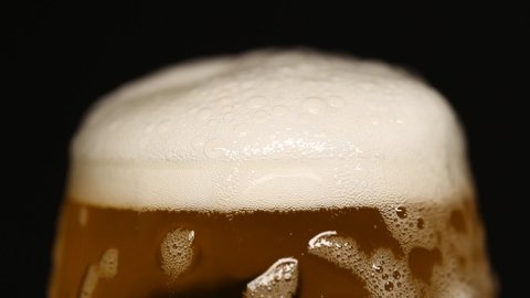 Beer foam is pouring over the edge in a bakery closeup. Black isolated background.