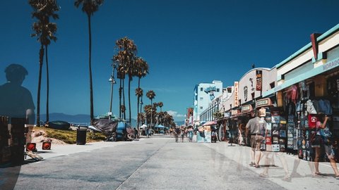 Los Angeles, USA. May 10, 2019. Vintage time lapse view of the Venice beach in California, LA. People walking down the Venice beach broadway near palms and blue skies on a sunny day. Retro style.