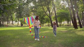 happy mother and daughter running with colorful kite in park