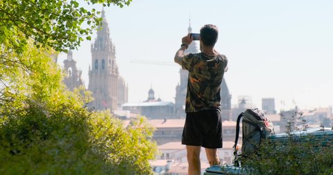 Male pilgrim taking photo of cathedral with mobile telephone in Santiago de Compostela, Spanish town at the end of Way of St James. Young man shooting picture on smartphone, cell phone