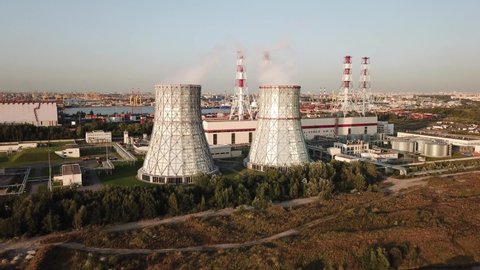 4K summer afternoon aerial drone video of new modern thermal power station, electricity producing plant, huge cooling water towers, located on outskirts of large city in northern hemisphere