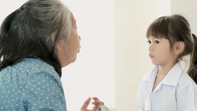 Asian little girl talk with her grandmother or old woman in front of white curtain with day light.