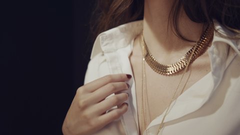 Luxury fashionable girl puts on gold jewelry around her neck. Trying on a gold chain around the neck. Jewelry advertising. Gold thick chain.