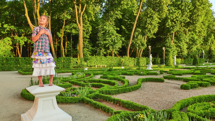Little girl is pretending to be statue. Branicki Palace is a historical edifice in Bialystok, Podlaskie Voivodeship, Poland. The palace complex with gardens, fountains, pavilions, sculptures.