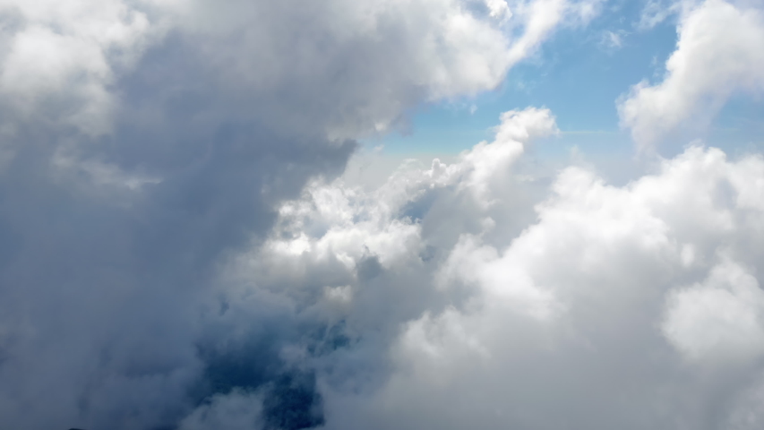 Flying through beautiful thick fluffy clouds. Amazing timelapse of soft white clouds moving slowly on the clear blue sky in pure daylight. Direct view from the cockpit. Royalty-Free Stock Footage #1036992296