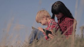 happy family concept Mother and son slow motion video. Mom girl and son Little boy with digital lifestyle internet tablet work and play the final light flare outdoors. life happy family care love