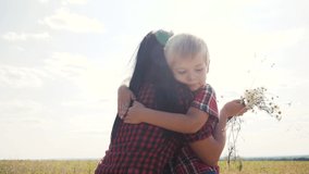happy family concept son hugs mom slow motion video. happy mother's day! baby son congratulates mother on holiday and gives flowers. boy son gives lifestyle girl mom bouquet of wildflowers sunlight
