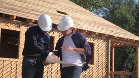 teamwork. concept building constructing architect slow motion video. two men builder in helmets study the house plan. two architects working on the construction of a frame house business contrast 