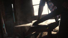 carpenter handmade and craft concept slow motion video. carpenter sawing lifestyle a tree in a workshop sawing sunlight from a window silhouette. woodworker engaged in processing wood at the sawmill