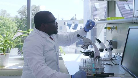 African-american scientist working in lab. Male doctor making microbiology research. Biotechnology, chemistry, bacteriology, virology, dna and health care.