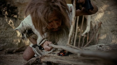 Primeval Caveman Wearing Animal Skin Trying to make a Fire with Bow Drill Method. Neanderthal Kindle First Man-Made fire in the Human Civilization History. Making Fire for Cooking. Slow Motion Closeup