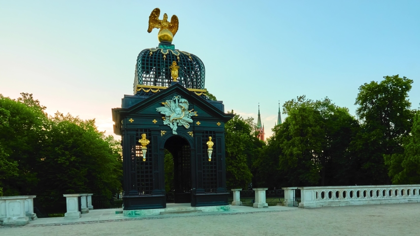 Little beautiful girl walks near main gate of Branicki Palace is historical edifice in Bialystok, Podlaskie Voivodeship, Poland. Palace complex with gardens, sculptures, and other structures.