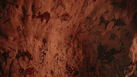 Primitive Prehistoric Neanderthal Drawings of Animals and Abstracts. Bonfire illuminating Walls at Night. Creating First Cave Art with Petroglyphs, Rock Paintings. Tilting Floating Camera Angle
