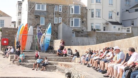 Saint Ive, Cornwall / England - 09/05/2019: People sitting near beach taking sun bath 