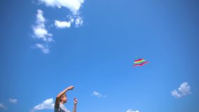 White kid playing colorful bright kite standing outdoor at sunny clear blue sky background. Slow motion full hd video footage.