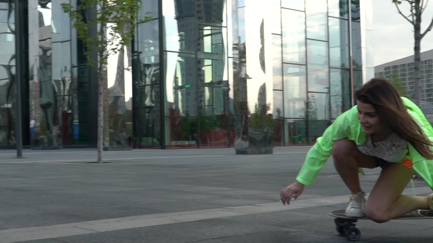 Girl rides sitting on a longboard in a circle. Slow motion video of a modern girl.	
