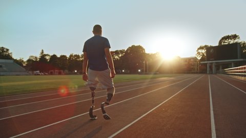 Athletic Disabled Fit Man with Prosthetic Running Blades is Walking During a Training on an Outdoor Stadium on a Sunny Afternoon. Amputee Runner Preparing for a Run. Motivational Sports Footage.