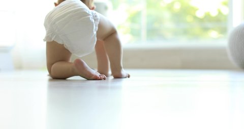 Little child crawling on floor at home, closeup