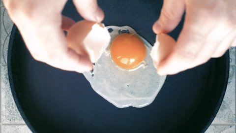 Fried eggs in a pan. Broken egg falls into the frying pan