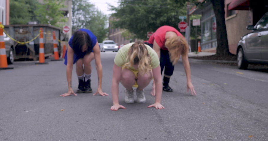 Close up of three women shuffling their feet in an urban dance in the streets of a city