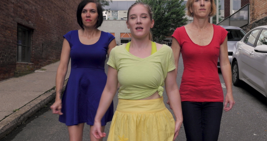 Three strong powerful women staring into the camera holding out their hands in a fist after a choreographed urban street dance