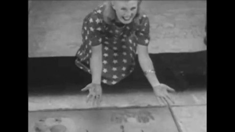 CIRCA 1940s Adolph Zukor puts his handprints, footprints, and signature in concrete at Grauman's Chinese Theater.