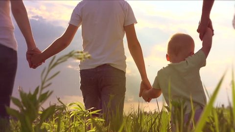 Happy Young Family with two children walking on summer field. Healthy mother, father and little sons enjoying nature together, outdoors. Slow motion 240 fps, high speed camera, Full HD 1080p