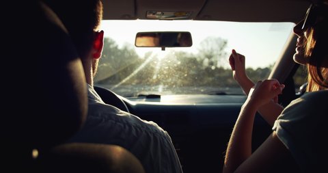 Cheerful boyfriend and girlfriend having fun and kissing in car, couple in love travelling