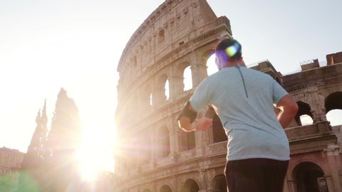 Young man running jogging in front of Colosseum at sunrise. Rome, Italy.