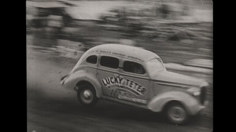 1930s Studebaker Drives Over Ramp and Jumps a Flatbed Truck while a Field of Spectators Cheer.  A Chevrolet Standard & Master Jumps 8 Cars before Wrenching and Flipping Over. 