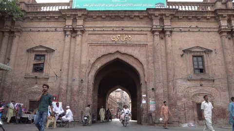 LAHORE, PAKISTAN - JUNE 2019: Historic Dehli Gate Frontal View with People Entering and Exiting on a Sunny Blue Sky Day