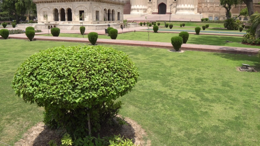 Lahore Alamgiri Gate Frontal View with Waving Pakistan Flag and Clipped Hedges on a Sunny Blue Sky Day