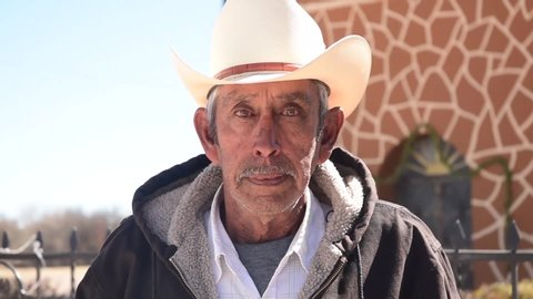 Older Mexican Man in front of Rural Church with Somber Look