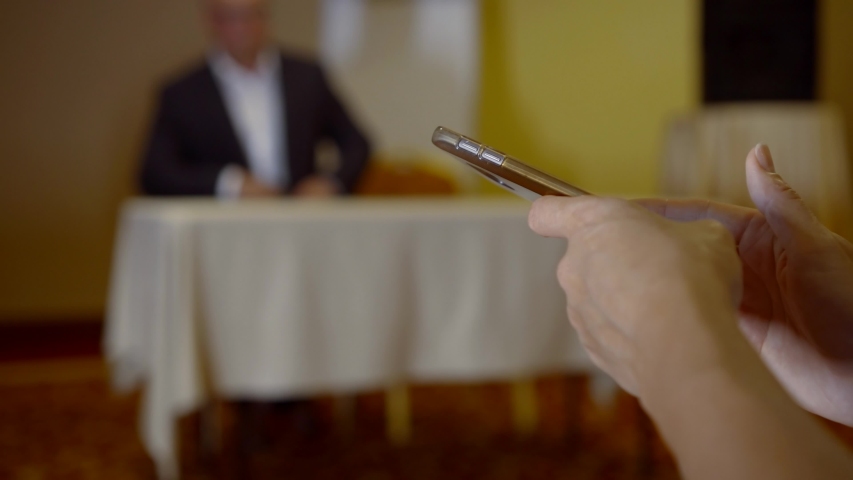 visitor of lecture or conference is making notes in mobile phone, typing on sensor display, closeup