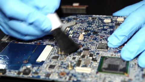 Asian Technician repair and cleaning dirty dust micro circuit main board computer electronic technology with brush : hardware, mobile phone, smartphone, upgrade concept.
