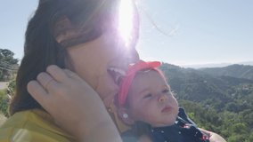 Slow motion of mother holding baby daughter in front of beautiful view