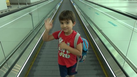 New Istanbul Airport, Turkey - 20th of August 2019: 4K Child waves good-bye and moves away on travelator
