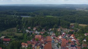 Aerial view of the village Betzenstein in Germany  on a sunny day in summer. Tilt down from the horizon to the village.