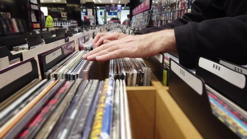 Browsing vinyl in a record store.

Close up of hands flipping through lps in a large record shop.