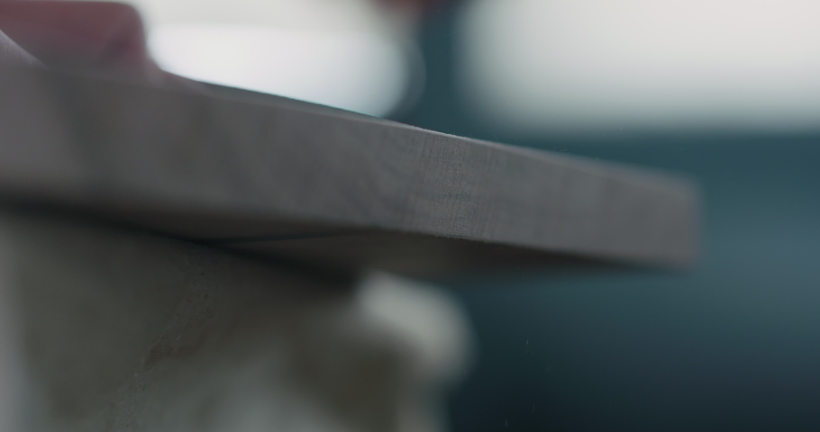 Slow motion woodworker hand sanding walnut board with sand block