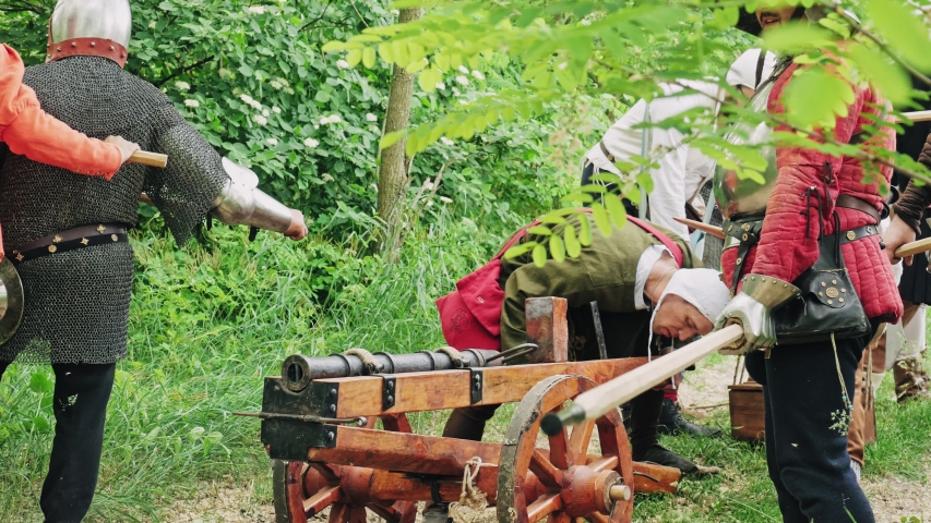 Warriors preparing to the attack and the artilleryist shoot from the cannon on the forest trail.