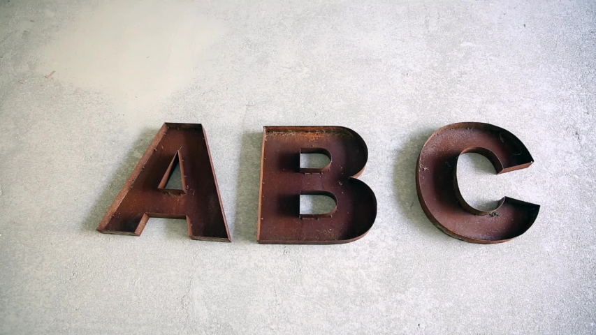 Rusty ABC letters taken away one by one on concrete floor