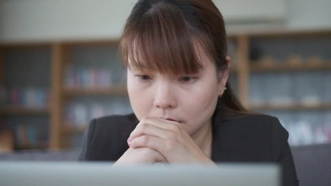 Portrait of worry Asian business woman looking at computer in office. A sad boss woman is unhappy as she fail business project & lost profit. She disappointed at employee. Sad & unsuccessful concept.