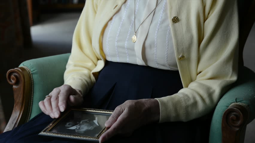 Elderly widow looking at old photograph of husband