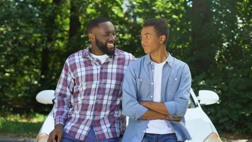 Happy dad giving car key to son, permission to drive, parenthood trust, family