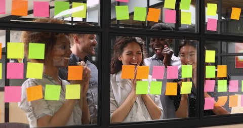 Happy overjoyed multiracial business team people group stand behind glass wall sticky notes celebrate corporate success victory good work result concept feel excited finished project job well done