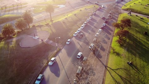 Aerial video of a white car on a road with traffic in the park on a sunny day located in Montevideo Uruguay