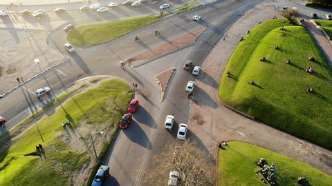 Aerial video of a white car on a road with traffic on the coast through park on a sunny day located in Montevideo Uruguay