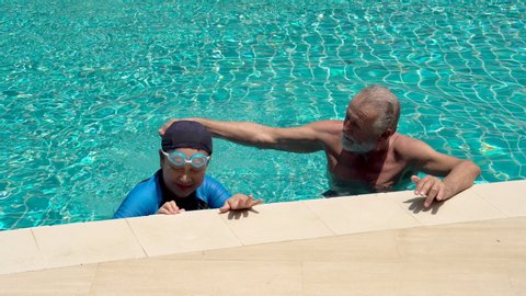Happy Senior Couple Relaxing In Swimming Pool Together. having fun . retirement,workout,fitness,sport,exercise . playful husband bullying wife