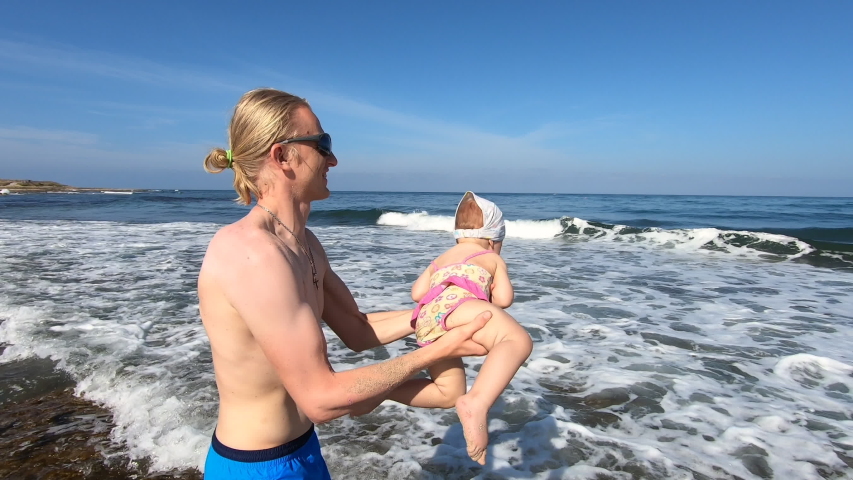 Happy father holding his daughter over his head and spinning. Active family having fun and enjoying beautiful sea view. Travel to Cyprus, Paphos